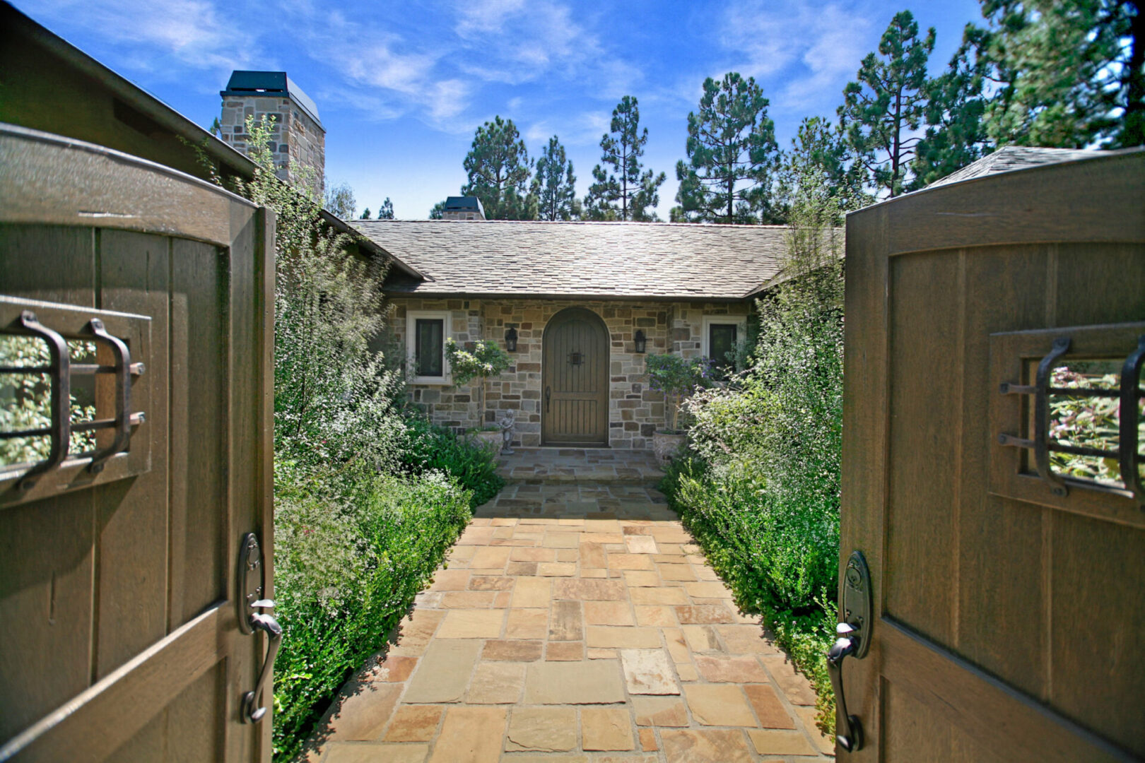 A stone walkway leading to a house with two doors.