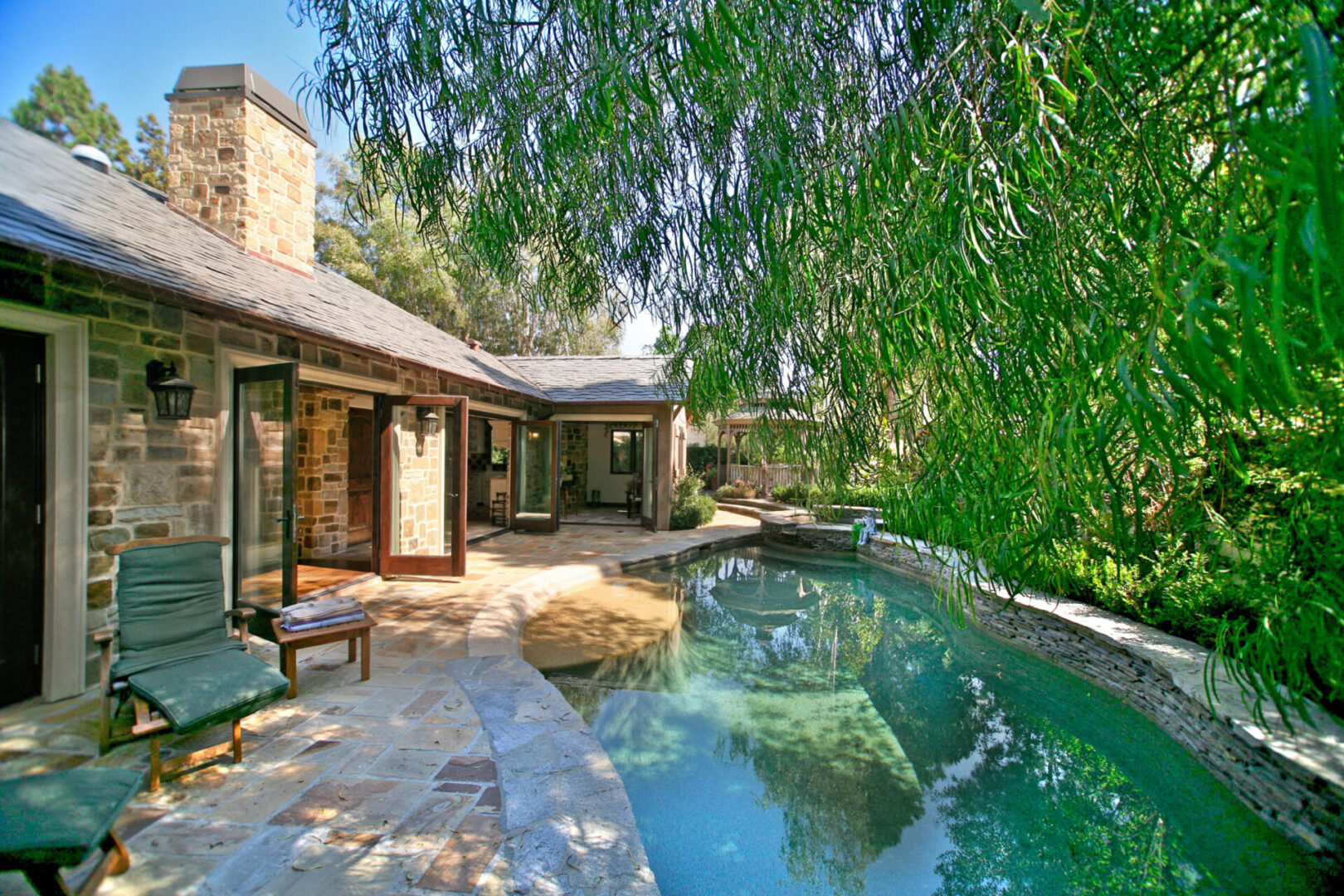 A pool with a bench and chairs in the back yard.