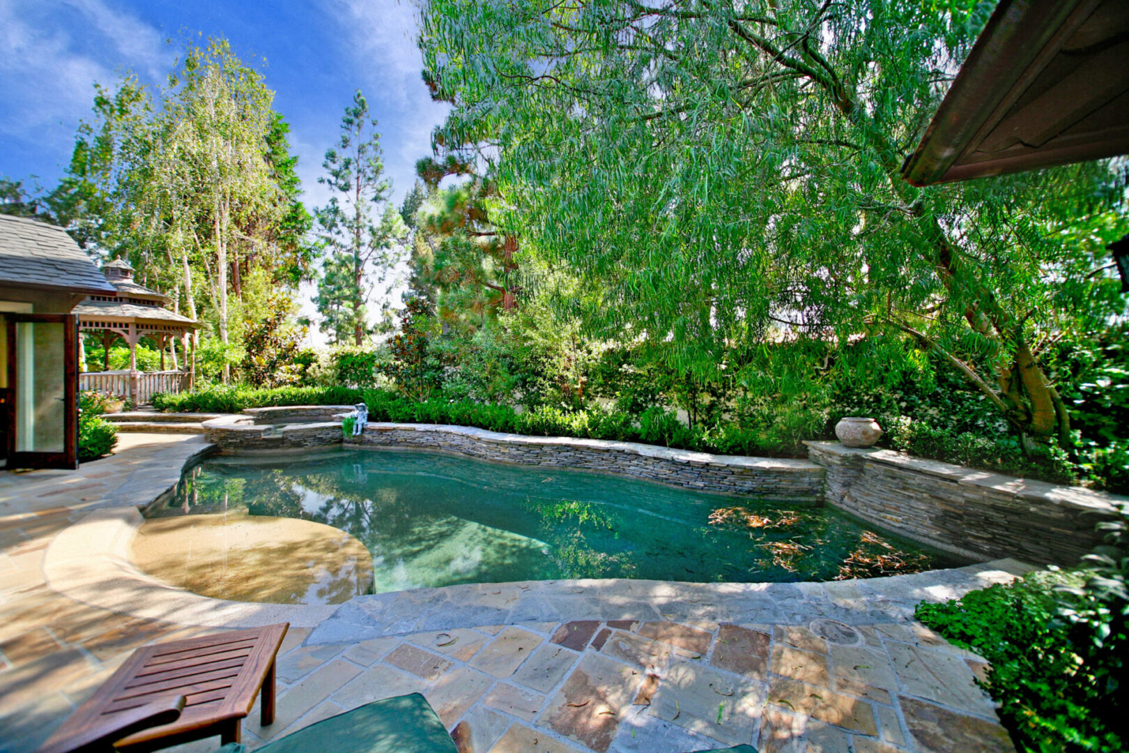 A pool with a bench and chairs in the middle of it.