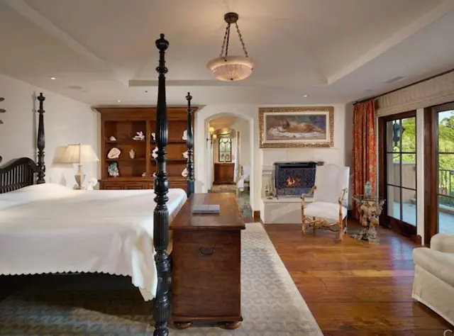 A bedroom with a fireplace and a large bed.