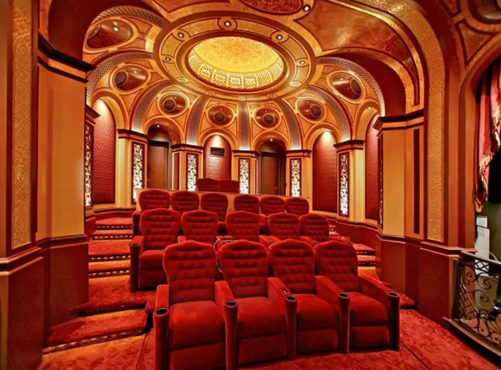 A theater room with red seats and gold ceiling.