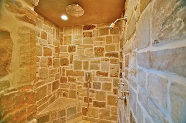 A stone shower with a tiled wall and ceiling.