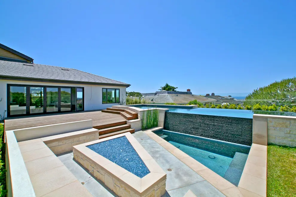 A pool with a large stone wall and a fire pit.