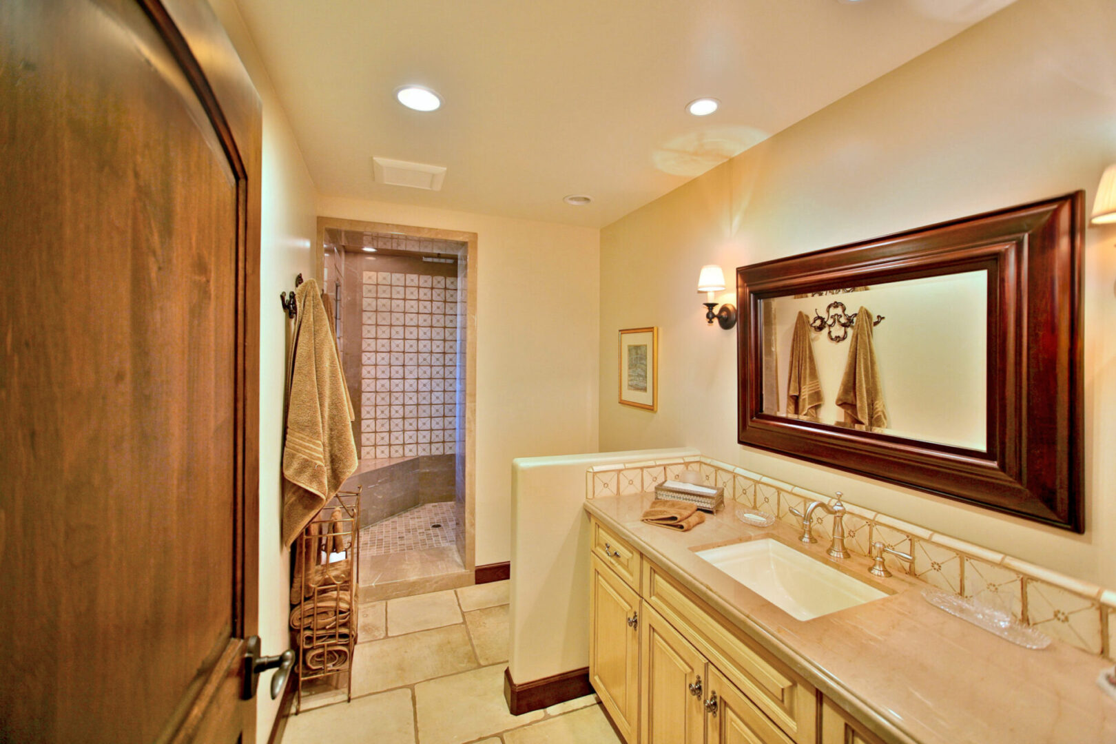 A bathroom with a sink, mirror and shower.