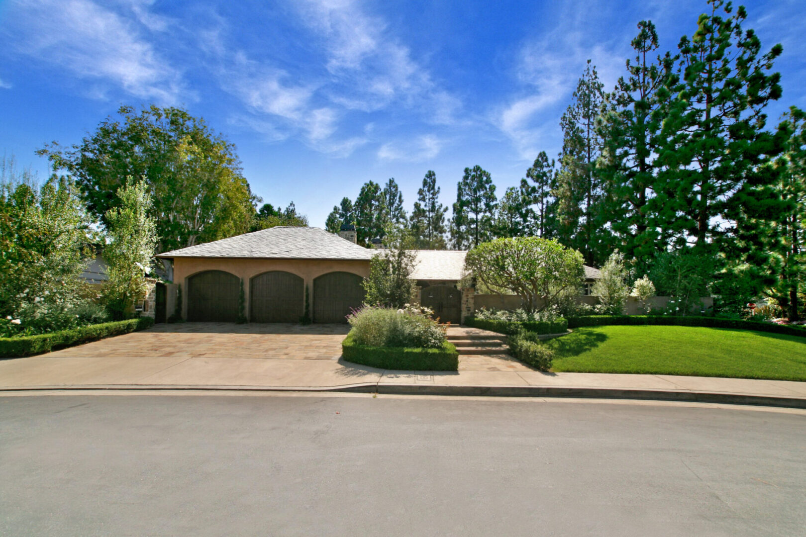 A large house with a driveway and trees in the background.